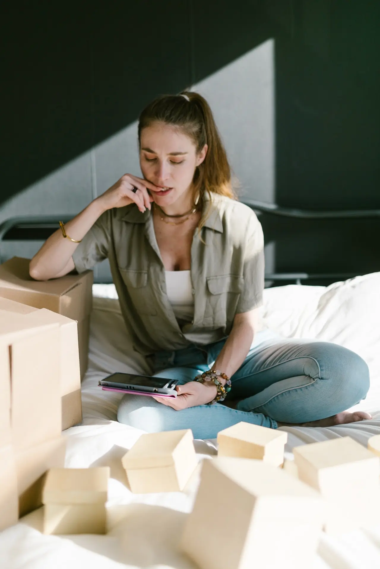 woman sitting on a bed with lots of packages around her